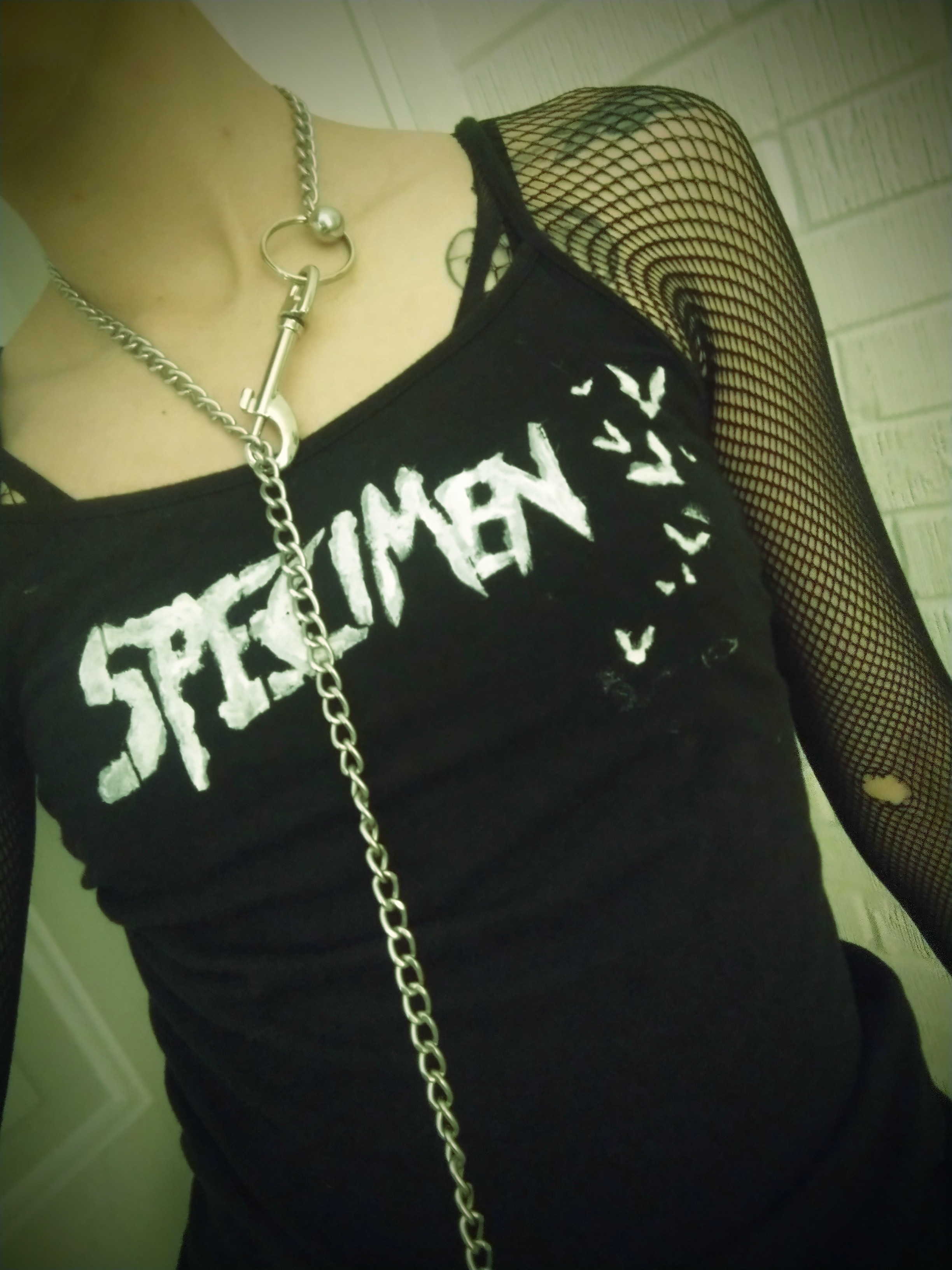 Torso of a person wearing a black tanktop with the band name Specimen on it